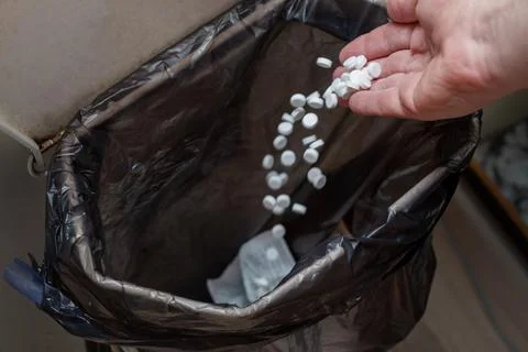 Throwing pills into the garbage - illegal disposal Stock Photos