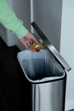 Throwing a plastic bottle into a large metal trash can. Sorting garbage at home. Фото