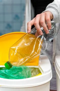 Throwing plastic bottle into a yellow sorting bin Fotos Stock