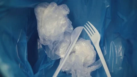 Throwing plastic disposable forks and knives into the blue garbage bag. Stock Footage 144121012