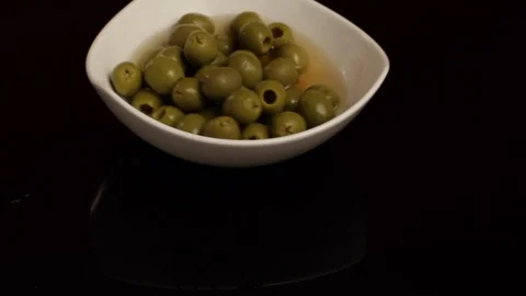 Throwing a Plate of Olives in a Black Surface Stock Footage 86136838