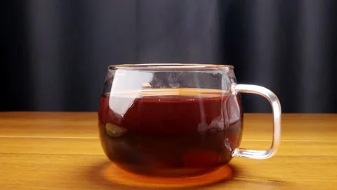 Throwing a sugar cube into the hot tea steaming in a glass mug 스톡 동영상 184603576