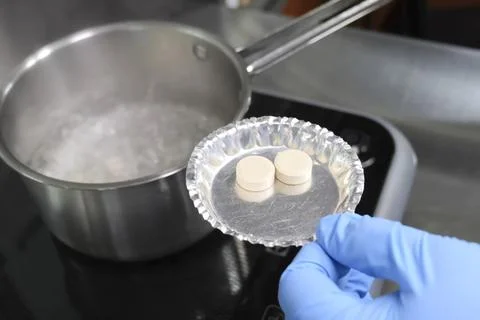 Throwing tablets with soup sublimate broth into boiling water. Fotos Stock