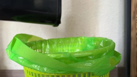 Throwing trash into green garbage bag in household trash bin Stock Footage 336977071