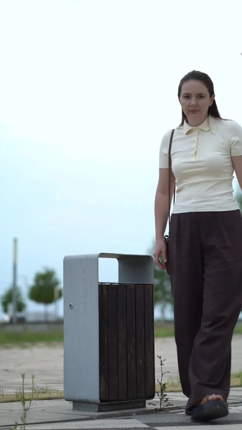 Throws empty plastic water bottle into outdoor metal and wood trash bin  Stock Footage 341409911