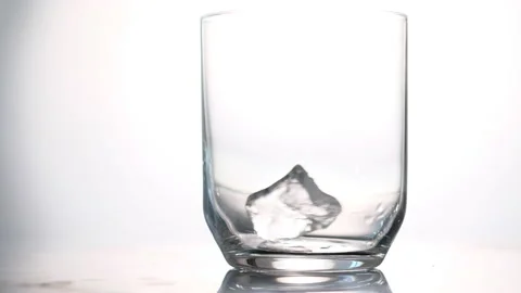 Throws ice cubes in a glass cup. Cold whiskey. Slow motion. Stock Footage 130741312
