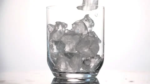 Throws ice cubes in a glass cup. Cold whiskey. Slow motion. Stock Footage 130741694