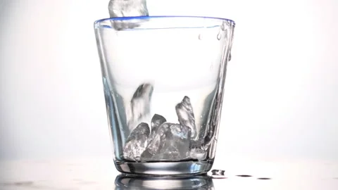 Throws ice cubes in a glass cup. Cold whiskey. Slow motion. Stock Footage 130741942