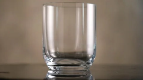 Throws ice cubes in a glass cup. Cold whiskey. Slow motion. Stock Footage 130781458