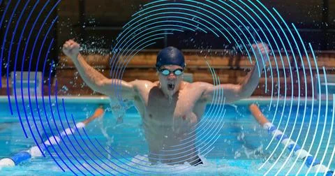 Thrusting male swimmer breaking surface in pool lane, wearing dark cap and Stock Photos