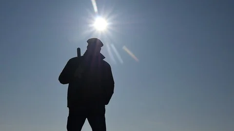 Thug with a bat slow approaching silhouette against sun Stock Footage 103468242