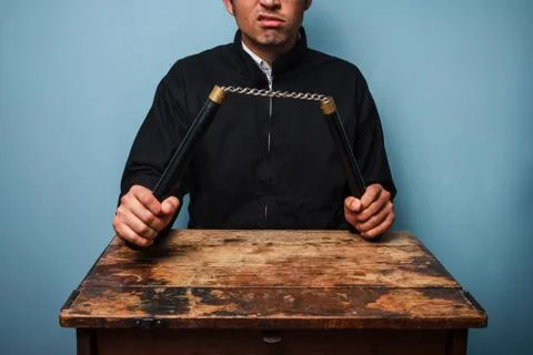 Thug at table with nunchucks Photos