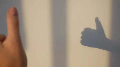 Thumb up against the background of sun rays, shadows and sunlight Video stock 285710050
