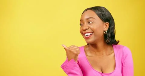 Thumb pointing back at copy space, beautiful Black woman, yellow studio Stock Photos