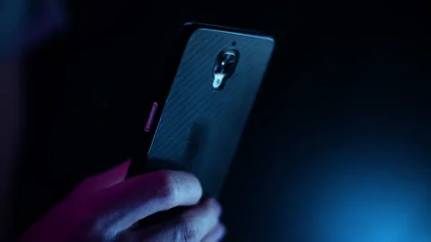 Thumb scrolling on a smartphone close up in a dark room with purple and blue Video stock 137102683
