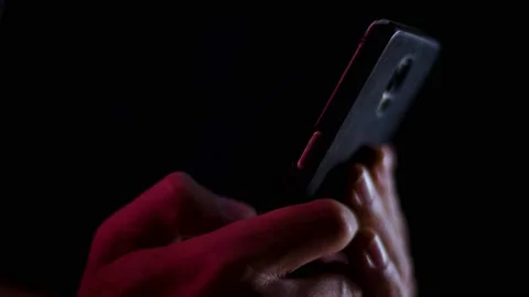 Thumb scrolling on a smartphone close up in a dark room with red and white l Stock Footage 137102720