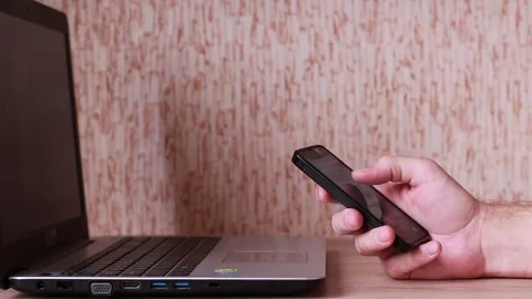 Thumbing through the smart phone in front of notebook Vídeo Stock 83532462
