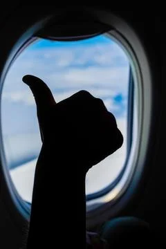 Thumbs up from airplane window during flight Stock Photos