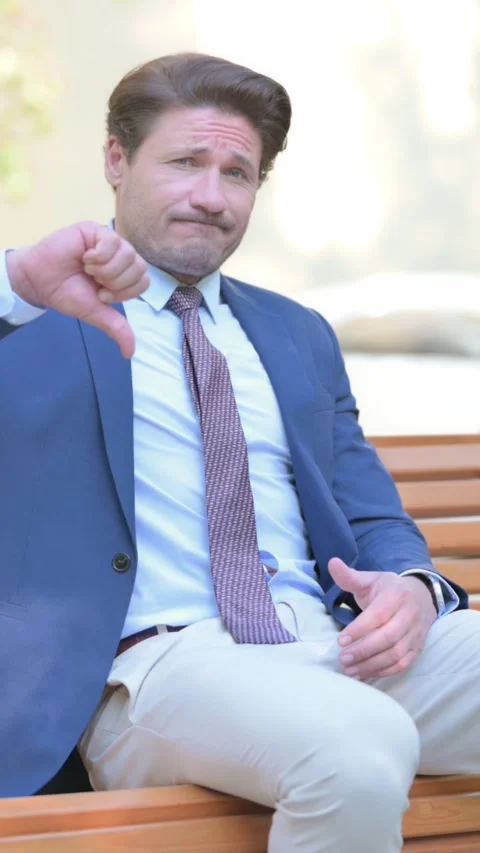 Thumbs Down by Businessman while Sititng Outdoor, vertical 스톡 동영상 321119539