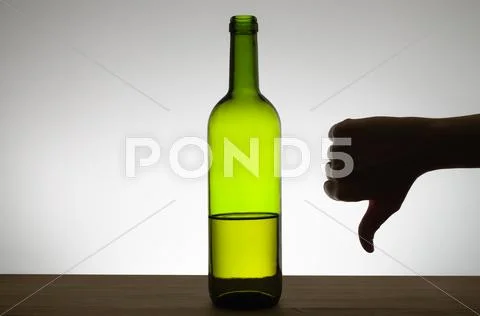 Thumbs down sign and a bottle of wine Stock Photos