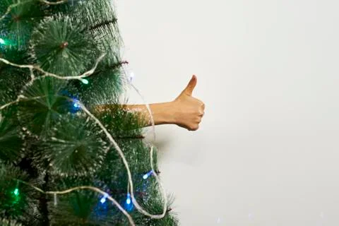 Thumbs-up gesture behind the Xmas tree Stock Photos