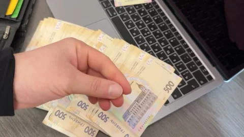 Thumbs-up hand in front of laptop and cash, symbolizing success. Stock Footage 307162398