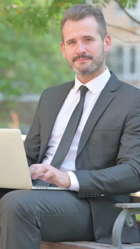 Thumbs Up by Middle Aged Businessman Using Laptop Outdoor on Bench, Vertical Video stock 319044904