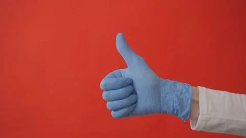 Thumbs up sign of approval in protective gloves on red background Stock Footage 146701563