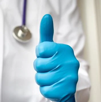 Thumbs up symbol by smiling young confident doctor. Stock Photos