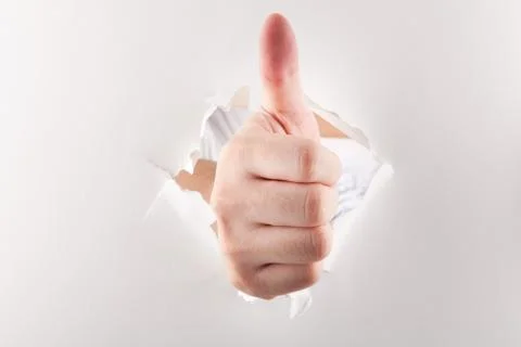 Thumbs up through paper Stock Photos
