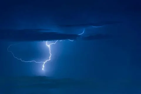 Thunder storm lightning strike on the dark cloudy sky background Photos