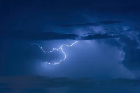 Thunder storm lightning strike on the dark cloudy sky background at night. Photos