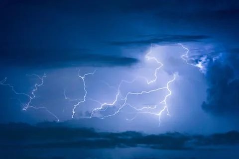 Thunder storm lightning strike on the dark cloudy sky background at night. Photos
