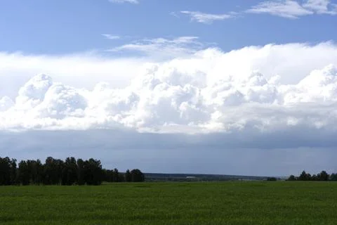 Thunderclouds on the background of a green field. A stormy landscape in the.. Stock Photos