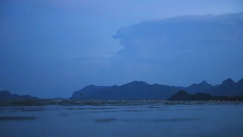 Thunderclouds glowing with lightning bolts over sea and mountains in dramatic Stock Footage 314408300