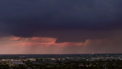 Thunderstorm clouds glowing from lightning over a dark colorful evening horizon. Stock Footage 304404024