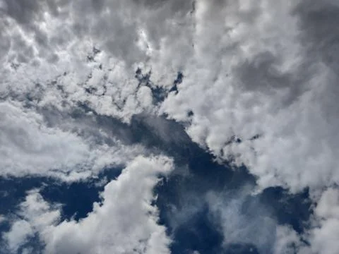 Thunderstorm clouds in the sky. White with gray. A piece of blue sky. Stock Photos
