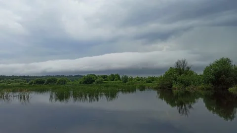 Thunderstorm is coming to lake. sky with clouds is reflected in still  water. Video stock 168537514