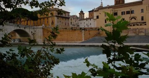 The Tiber flows under a historic bridge, framed by greenery in Rome, Italy. Stock Footage 297786566