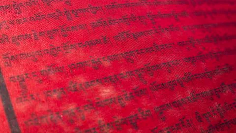 Tibetan letters on red textile. Religious writing. Prayer flags. Mantra. Stock Photos