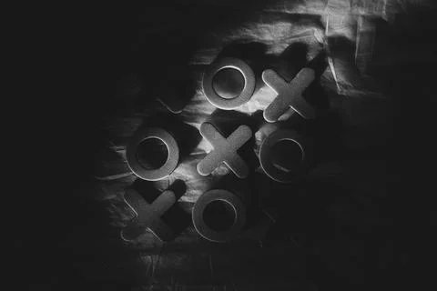 Tic-tac-toe on a dark background with dramatic lighting. Tabletop game, tacti Stock Photos