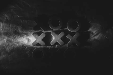 Tic-tac-toe on a dark background with dramatic lighting. Tabletop game, tacti Stock Photos