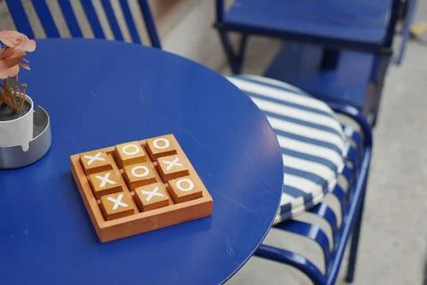 Tic-tac-toe game on blue table with chairs in a casual setting Stock Photos