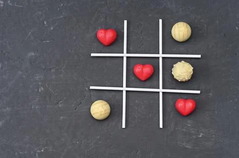 Tic-tac-toe game displayed using red heart shapes and round candies, Foto stock