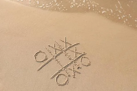 Tic tac toe game drawn on sand near sea, top view. Space for text Stock Photos