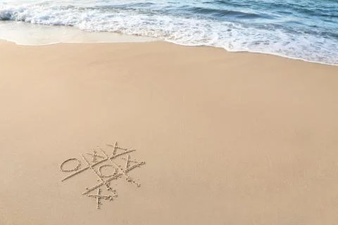 Tic tac toe game drawn on sand near sea, space for text Stock Photos
