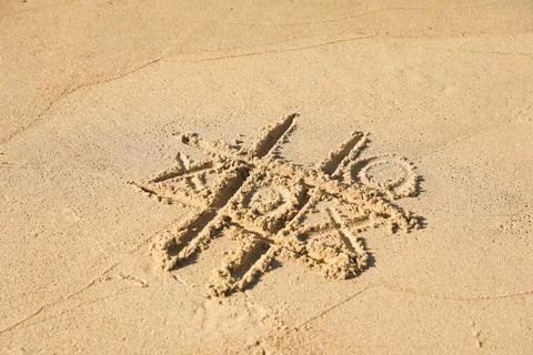 Tic tac toe game drawn on sandy beach Stock Photos