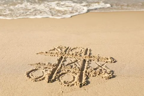 Tic tac toe game drawn on sand near sea, space for text Stock Photos