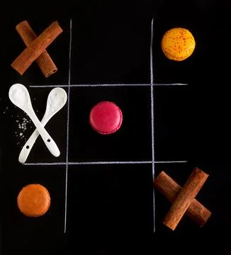 A tic tac toe game with macarons and cinnamon sticks Stock Photos