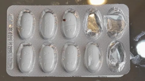 Tick crawling on Apocillin antibiotic tablet in blister pack symbolizing 스톡 동영상 319519974